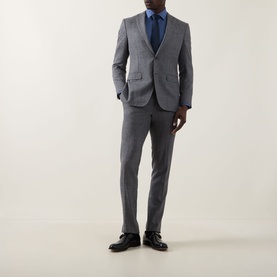 Model wearing Calvin Klein The Poplin Slim Fit Shirt in blue, styled with a grey slim-fit suit, navy tie, and black leather shoes.