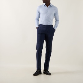 Model wearing Calvin Klein Check Slim Fit Non-Iron Shirt in blue with navy slim-fit trousers and black leather shoes.