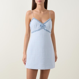 Model wearing light blue slip mini dress with spaghetti straps, V-neckline, decorative bow and lace trim detail