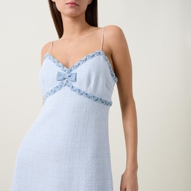 Model wearing pale blue textured boucl&eacute; slip dress with bow detail, frilled trim neckline and thin straps