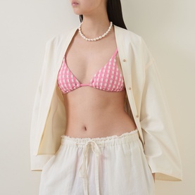 Model wearing Seafolly Begonia Pink gingham triangle bikini top with pearl necklace, styled with cream shirt and white drawstring trousers.