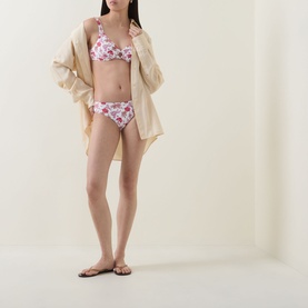 Model wearing Seafolly ecru floral bikini top with matching briefs, styled with an open beige shirt and brown flip-flops