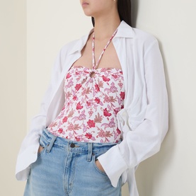 Model wearing Seafolly ecru floral halterneck swimsuit with gathered bust detail, styled with white shirt and blue denim jeans.