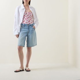 Model wearing Seafolly ecru floral swimsuit styled with light blue denim shorts, white oversized shirt and brown flip flops