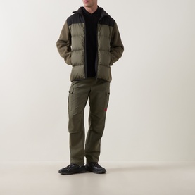 Model wearing Boss Green Label Open Green puffer jacket with black hood, styled with matching cargo trousers and black shoes.