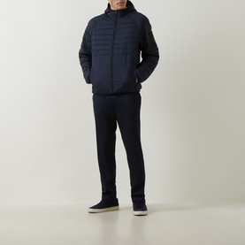 Model wearing Boss Green Label dark blue quilted padded jacket with funnel neck, styled with navy trousers and cream trainers.