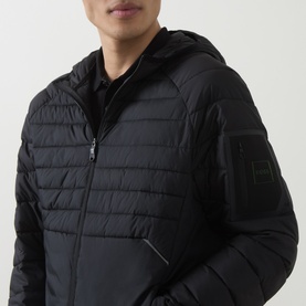 Model wearing Boss Green Label black quilted hooded jacket with zip pockets and logo sleeve patch, styled with black polo shirt.