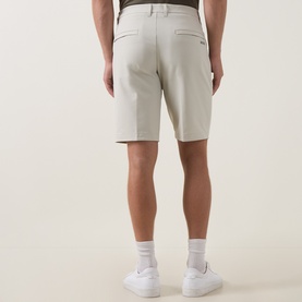 Model wearing Boss Green Label Commuter 10.5" Golf Shorts in Light Beige, slim fit, rear view, styled with white trainers and socks.