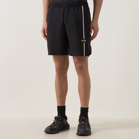 Model wearing Boss Green Label TOC Game 8" Golf Shorts in black with white stripe detail, styled with black chunky trainers