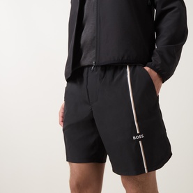 Model wearing Boss Green Label TOC Game 8" Golf Shorts in black with pink side stripe detail and logo print, styled with a black jacket.