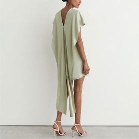 Model wearing Reiss grey dress with V-back detail and draped fabric, styled with white strappy heeled sandals