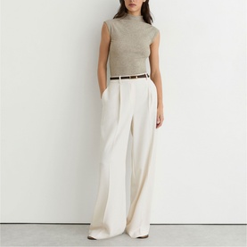 Model wearing Reiss wide-leg trousers in cream with pleat detail and tan belt, styled with a grey sleeveless mock-neck top