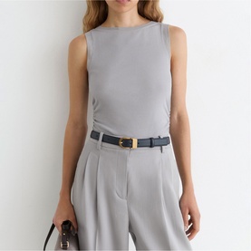 Model wearing Reiss grey sleeveless top with wide-leg trousers, navy belt with gold buckle, carrying a brown bag.