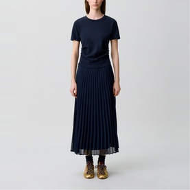 Model wearing Claude Pierlot blue short-sleeve top and navy pleated midi skirt, styled with gold lace-up ankle boots