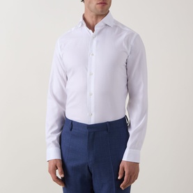 Model wearing Eton Signature Oxford Shirt in white with wide spread collar and buttoned cuffs, styled with navy blue trousers.