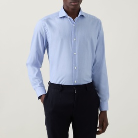 Model wearing Eton Signature Oxford Shirt in light blue with wide spread collar and long sleeves, styled with navy trousers.