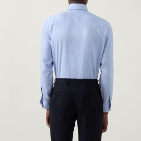 Model wearing Eton Signature Oxford Shirt in light blue, rear view, showing plain back yoke and buttoned cuffs, styled with navy trousers.