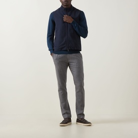 Model wearing Eton Lana Technical Gilet in navy blue with high neck and two-way zip, styled with blue knit and grey trousers.