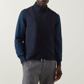 Model wearing Eton Lana Technical Gilet in navy blue, sleeveless with high neck and zip fastening, styled over a navy long-sleeve top with grey