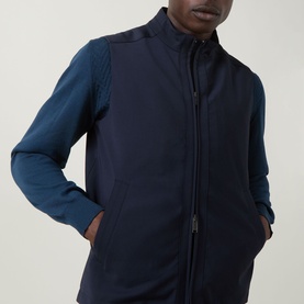 Model wearing Eton Lana Technical Gilet in navy blue with high neck and zip fastening, styled with a teal long-sleeve top underneath