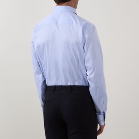 Model wearing Eton Solid Single-Cuff Shirt in light blue cotton, rear view, with single cuffs, paired with dark navy trousers.