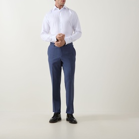 Model wearing Eton Twill Single Cuff Shirt in white with pointed collar, styled with blue tailored trousers and black dress shoes.