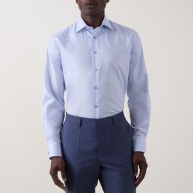 Model wearing Eton Prince of Wales Check Shirt in light blue, cut-away collar, long sleeves, styled with navy trousers.