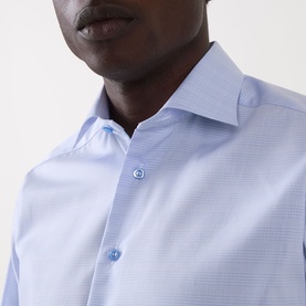 Model wearing Eton Prince of Wales Check Shirt in light blue, featuring cut-away collar and button fastening, close-up chest detail view.