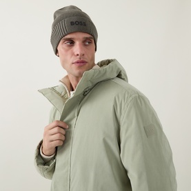Model with Hugo Boss Asic Logo Beanie Hat in Open Green, ribbed knit with rubberised 3D logo, styled with a light green padded jacket