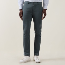 Model wearing Hugo Boss Orange Open Green slim-fit cotton chino trousers, styled with a white shirt and white trainers.