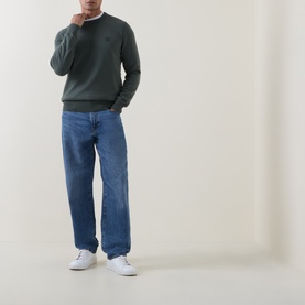 Model wearing Hugo Boss Orange Open Green cotton cashmere crew neck jumper, styled with blue wide-leg jeans and white trainers.