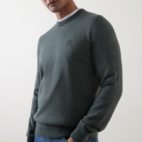 Model wearing Hugo Boss Orange Open Green cotton-cashmere crew neck jumper with tonal chest logo, styled with white tee and blue jeans.
