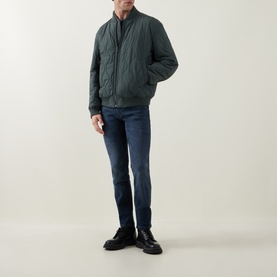 Model wearing Hugo Boss Orange Osual Wave Quilted Bomber Jacket in Open Green, styled with dark blue jeans and black boots