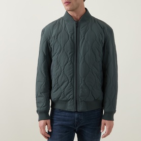 Model wearing Hugo Boss Orange Osual Wave Quilted Bomber Jacket in Open Green, styled with blue jeans. Wave-quilted shell, zip-through, elasticated