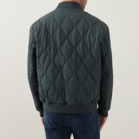Model wearing Hugo Boss Orange Osual Wave Quilted Bomber Jacket in Open Green, rear view, styled with blue jeans