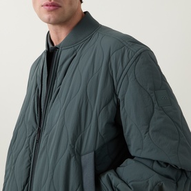 Model wearing Hugo Boss Orange Osual Wave Quilted Bomber Jacket in Open Green, close-up showing wave-quilted texture and zip-through collar