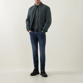 Model wearing Hugo Boss Orange Osual Wave Quilted Bomber Jacket in Open Green, styled with dark blue jeans and black shoes