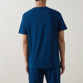 Model wearing blue crew neck T-shirt, rear view, styled with matching blue trousers