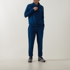 Model wearing Hugo Boss turquoise zip-up track top with matching joggers and grey trainers.