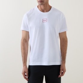 Model wearing Hugo Laze Logo Lounge T-Shirt in white with crew neck, small red logo box print on chest, styled with black trousers.