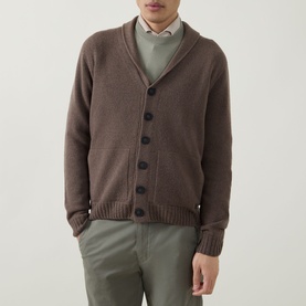 Model wearing John Smedley Rockford Shawl Cardigan in light brown with button fastening, styled with sage green trousers and collared shirt.