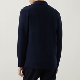 Model wearing John Smedley Narah Knit Cardigan in navy, rear view showing long sleeves and structured knit, styled with black trousers