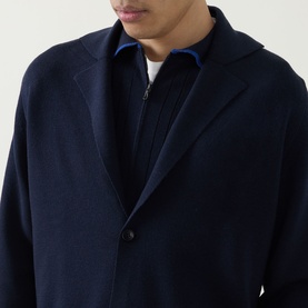 Model wearing John Smedley Narah Knit Cardigan in navy, notched lapels, button fastening, styled over blue zip-neck knitwear.
