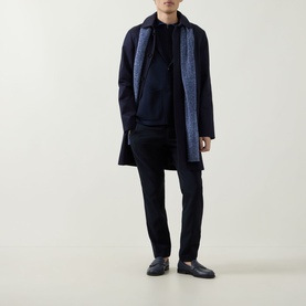 Model wearing John Smedley Narah Knit Cardigan in navy, styled with a navy coat, scarf, trousers and black loafers.