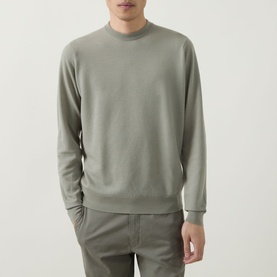 Model wearing John Smedley 15.Singular Knit Sweater in Thistle Drew, crew neck merino wool jumper with ribbed trims, styled with sage trousers.