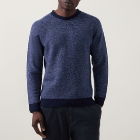 Model wearing John Smedley Winslow Textured Knit Sweater in Blueprint Midnight, crew neck, ribbed trims, paired with dark trousers.