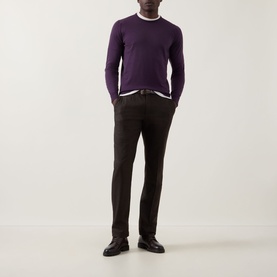 Model wearing John Smedley Lundy Extra Fine Knit Sweater in Velvet Plum, styled with dark trousers and a white crew neck tee.