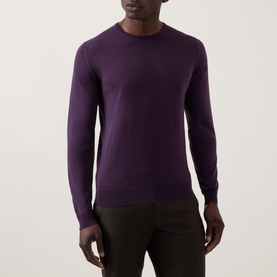 Model wearing John Smedley Lundy Extra Fine Knit Sweater in Velvet Plum, crew neck with ribbed trims, paired with dark trousers.