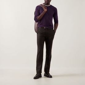 Model wearing John Smedley Lundy Extra Fine Knit Sweater in Velvet Plum, styled with dark trousers and black leather shoes.