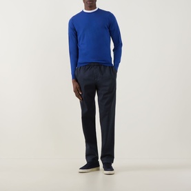 Model wearing John Smedley Lundy Extra Fine Knit Sweater in Mazarine Blue with navy trousers and light grey trainers.